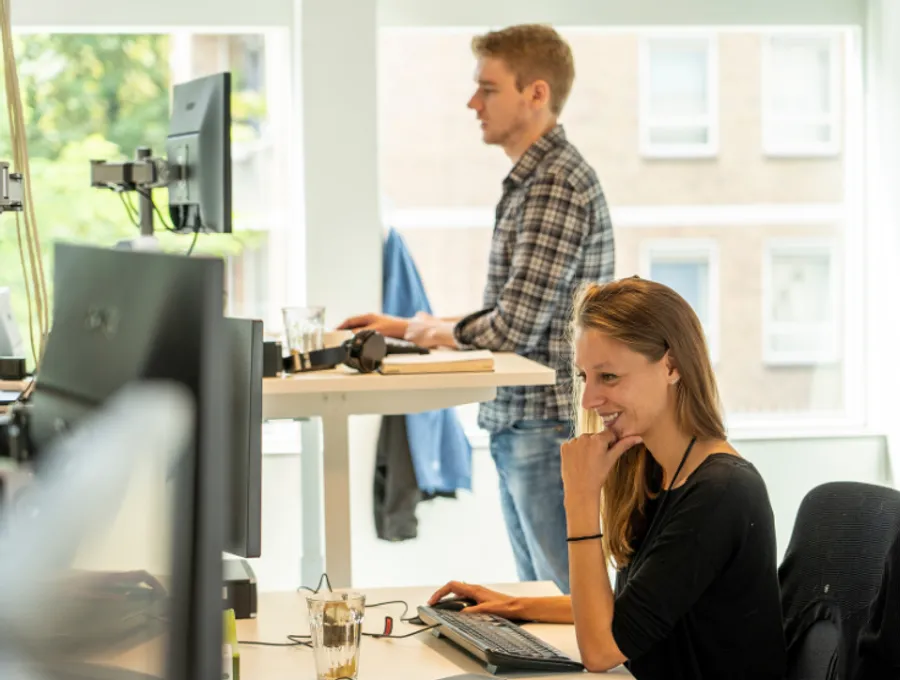 RS-Finance-werken-bij-RS-2 Twee medewerkers van RS Finance staand en zittend aan het werk.