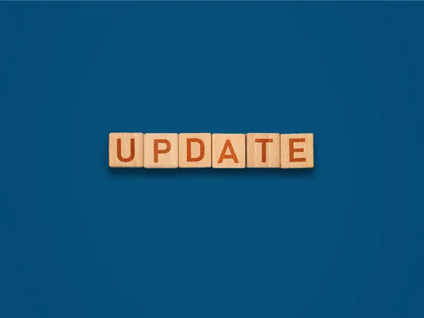 Houten blokken die het woord "update" spellen op een blauwe achtergrond.