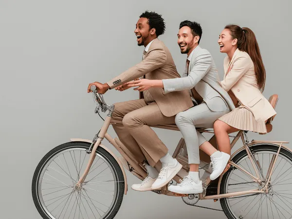 Drie zakenmensen rijden samen op een fiets (beeld gegenereerd door AI)