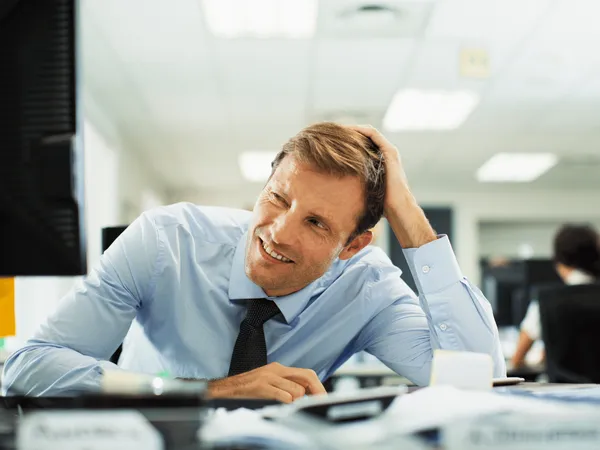 Zakenman staart met toegeknepen ogen naar computerscherm op kantoor.