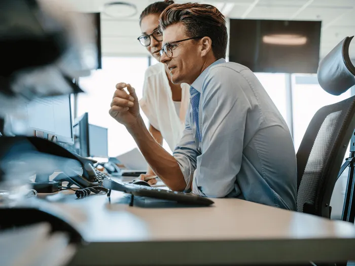 RS-blog-BDC-Shopify-Exact Twee collega’s die samen aan een bureau werken en naar hun computerscherm kijken.